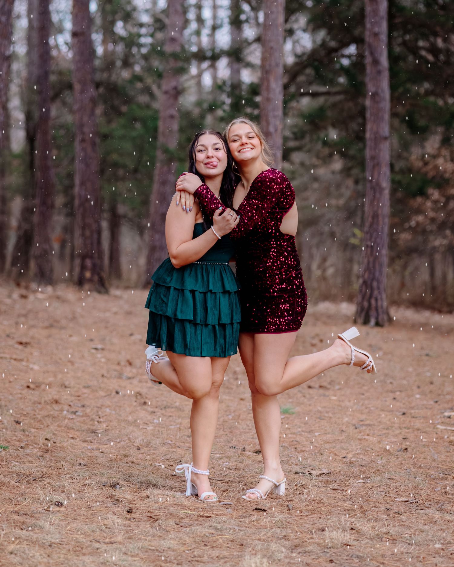 Two dancers in ballet shoes striking elegant poses among tall pine trees in a forest setting.