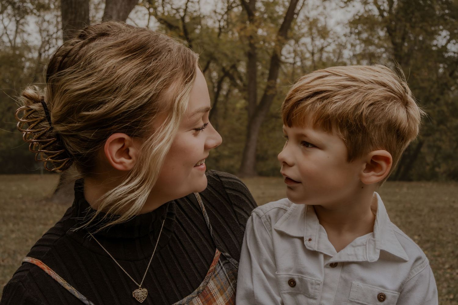 A candid moment captured outdoors showing a warm interaction between two people on an autumn day.