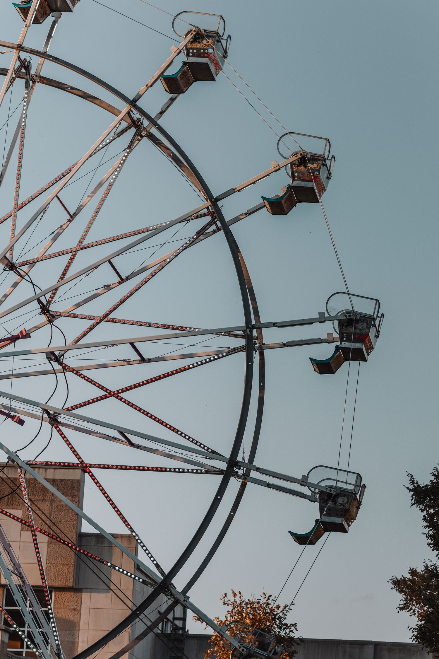 Aerial view of a vintage chairlift ride at an amusement park against a pale blue sky.