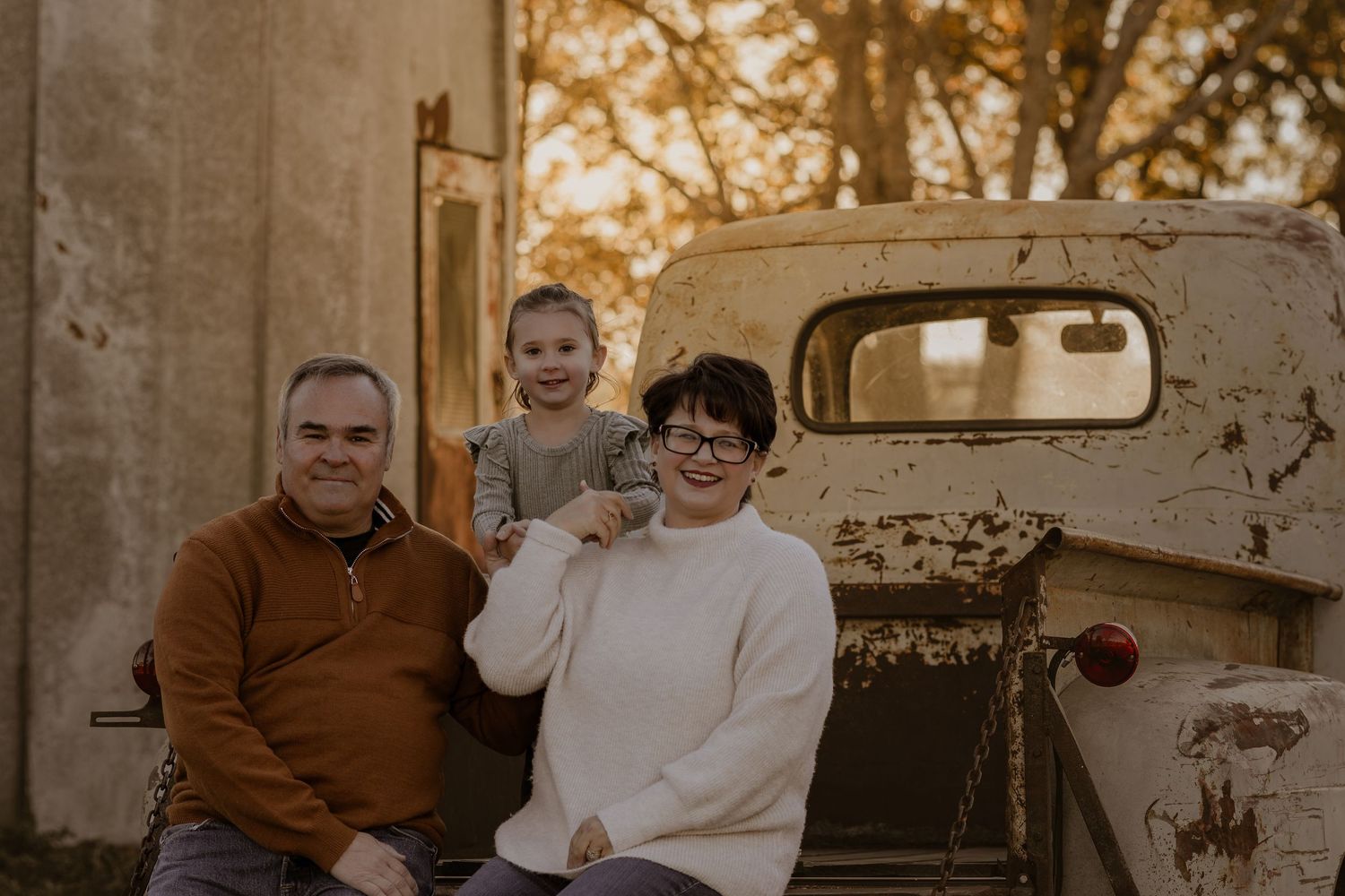 Family members share a relaxed moment together near a vintage vehicle during sunset.