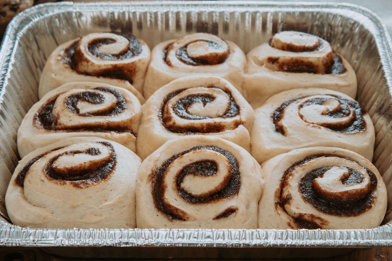 Freshly baked cinnamon rolls with swirls of brown sugar and cinnamon filling in a metal baking pan.
