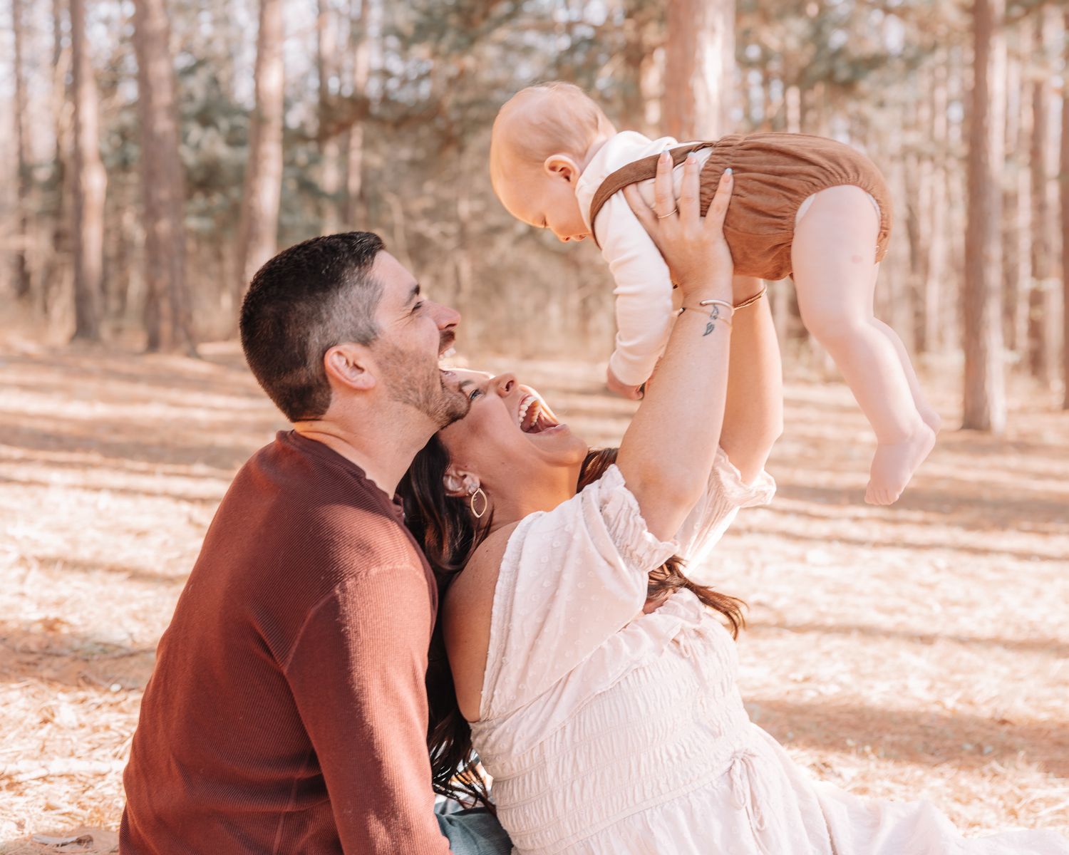 Candid family photo session taking place in a sunlit forest setting.