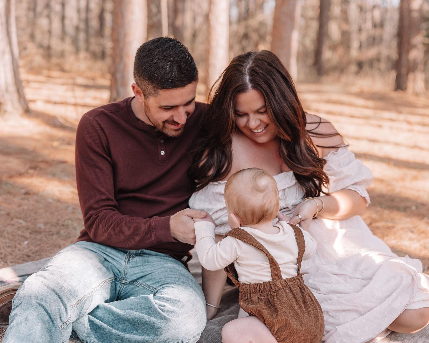 Family portrait series in warm autumn tones showing tender moments together in a wooded setting.