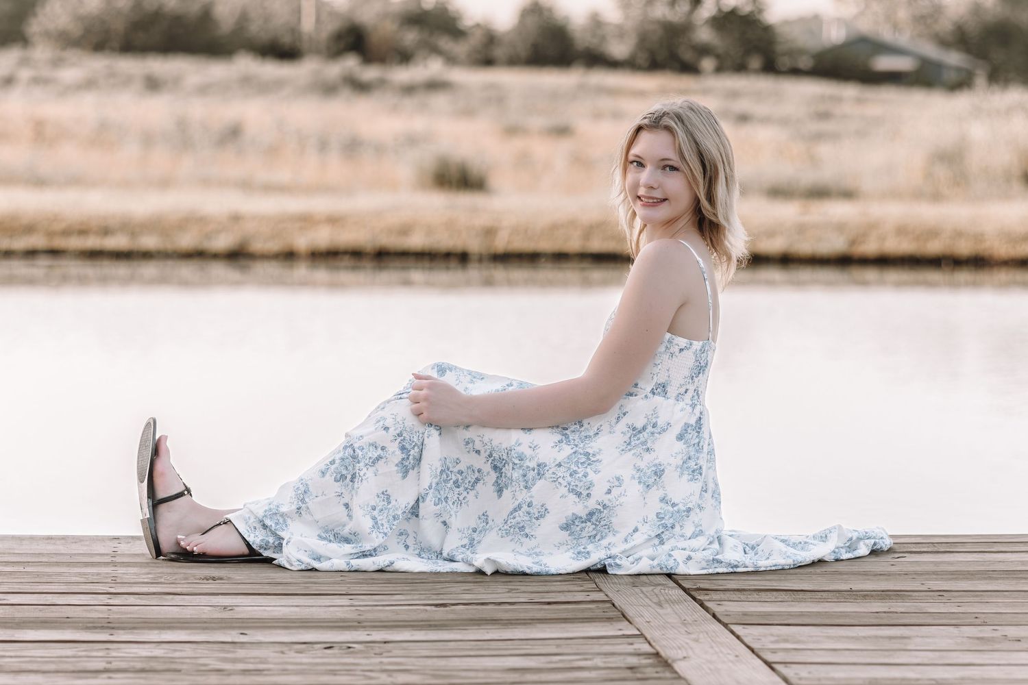 A delicate floral dress creates elegant lines against weathered wooden dock planks.