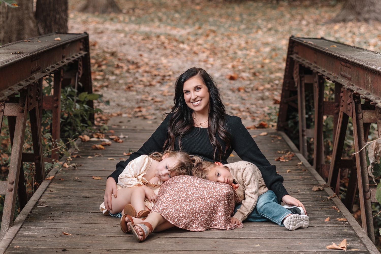 A series of lifestyle photos showing someone in a pink sequin dress laying on a wooden bridge surrounded by autumn leaves.