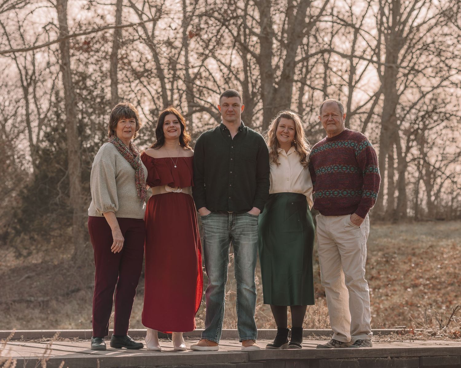A group of people in coordinated casual outfits pose together outdoors during an autumn photoshoot.