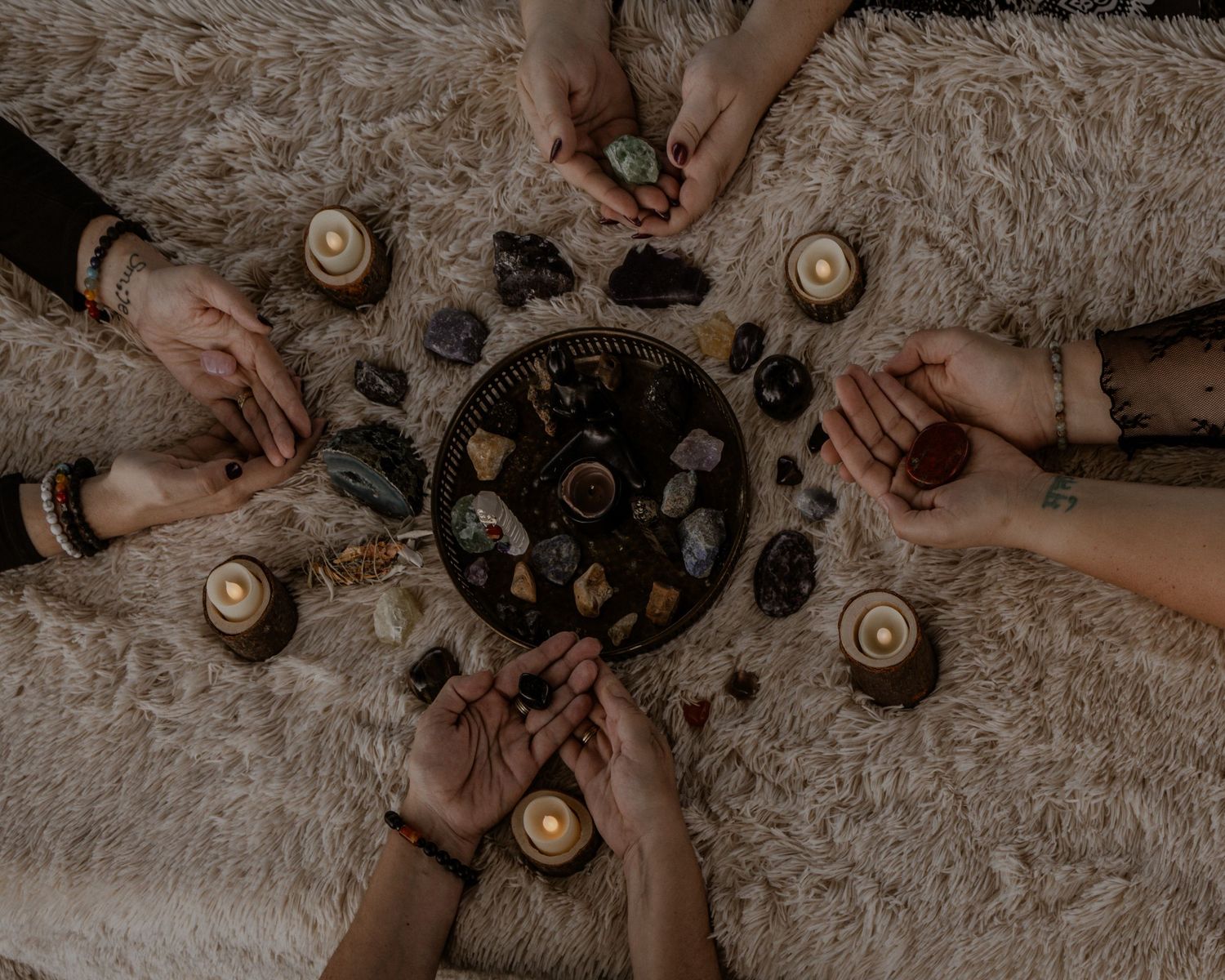 Aerial view of hands arranging candles and decorative elements on a textured blanket.