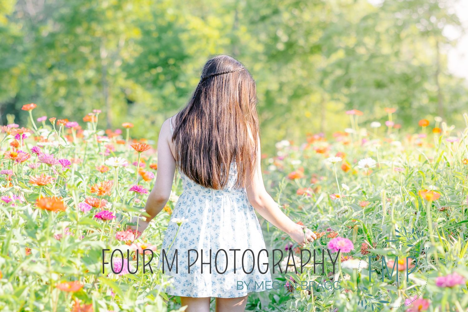 A person sits in a field of vibrant wildflowers during a sunny summer day, creating a dreamy outdoor portrait scene.