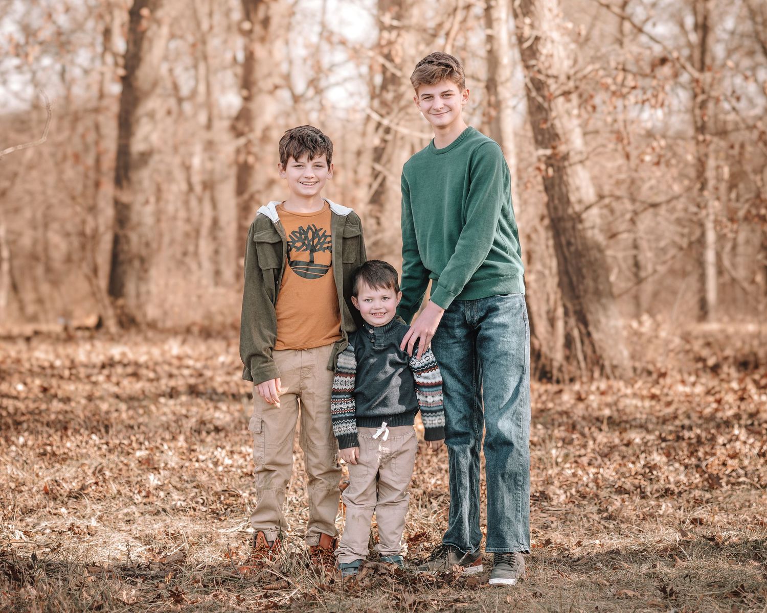 Family walking together through fallen leaves in an autumn forest setting.