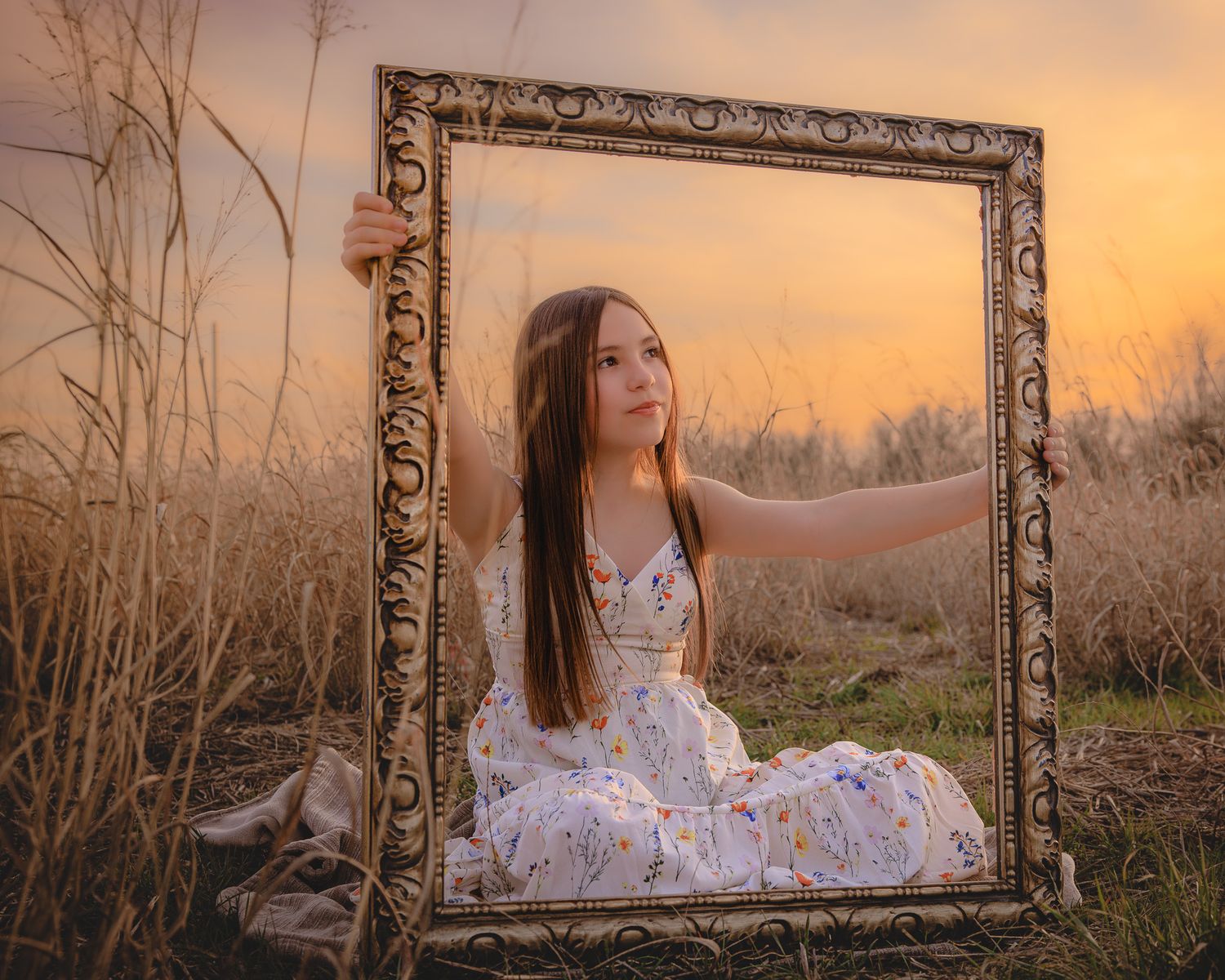 Artistic outdoor portrait series with vintage frame prop against golden sunset in tall grass field.