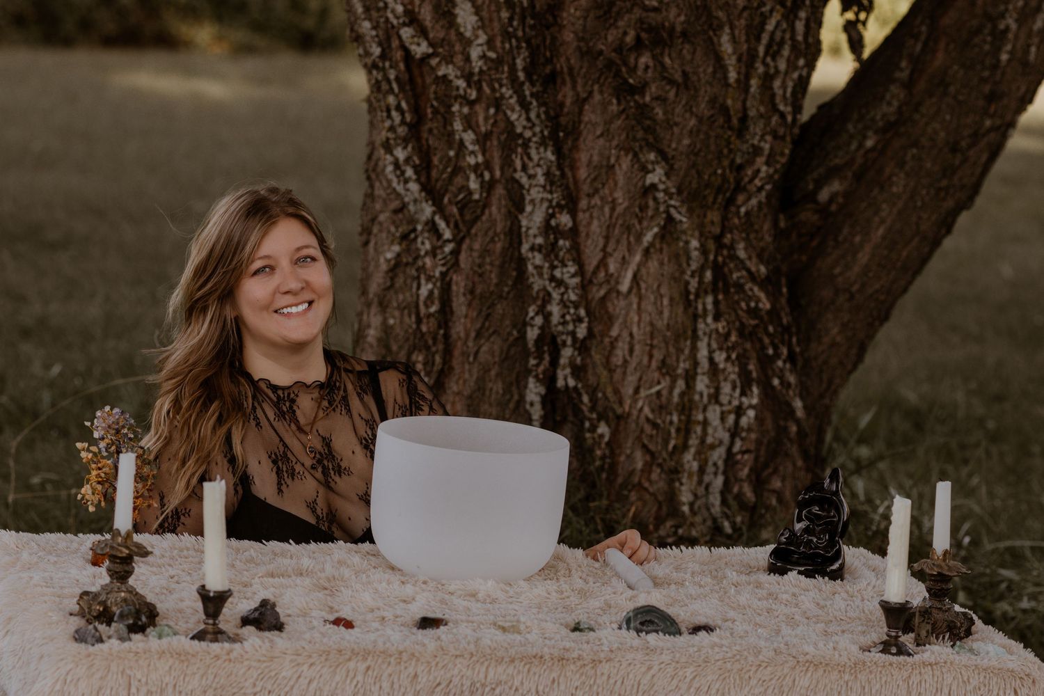 Outdoor photo session setup with candles and decorations against a large tree trunk.