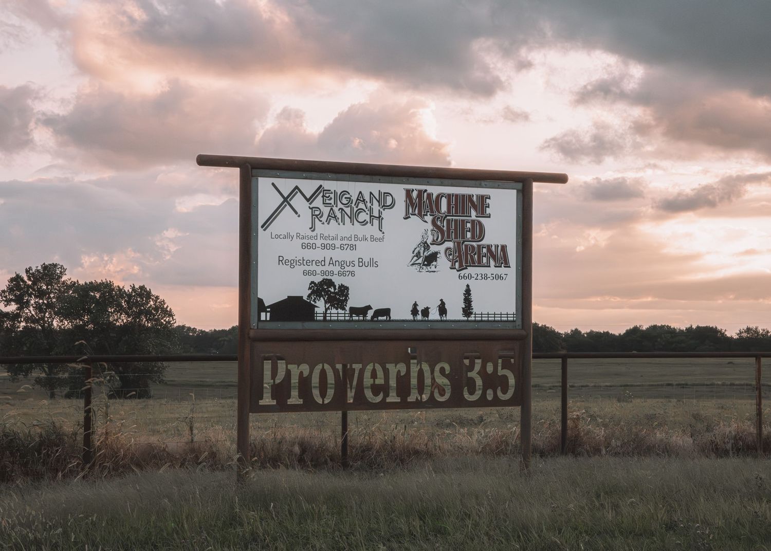 Weigand Ranch and Machine Shed Arena sign with Proverbs 3:5 scripture in a rural field at sunset.
