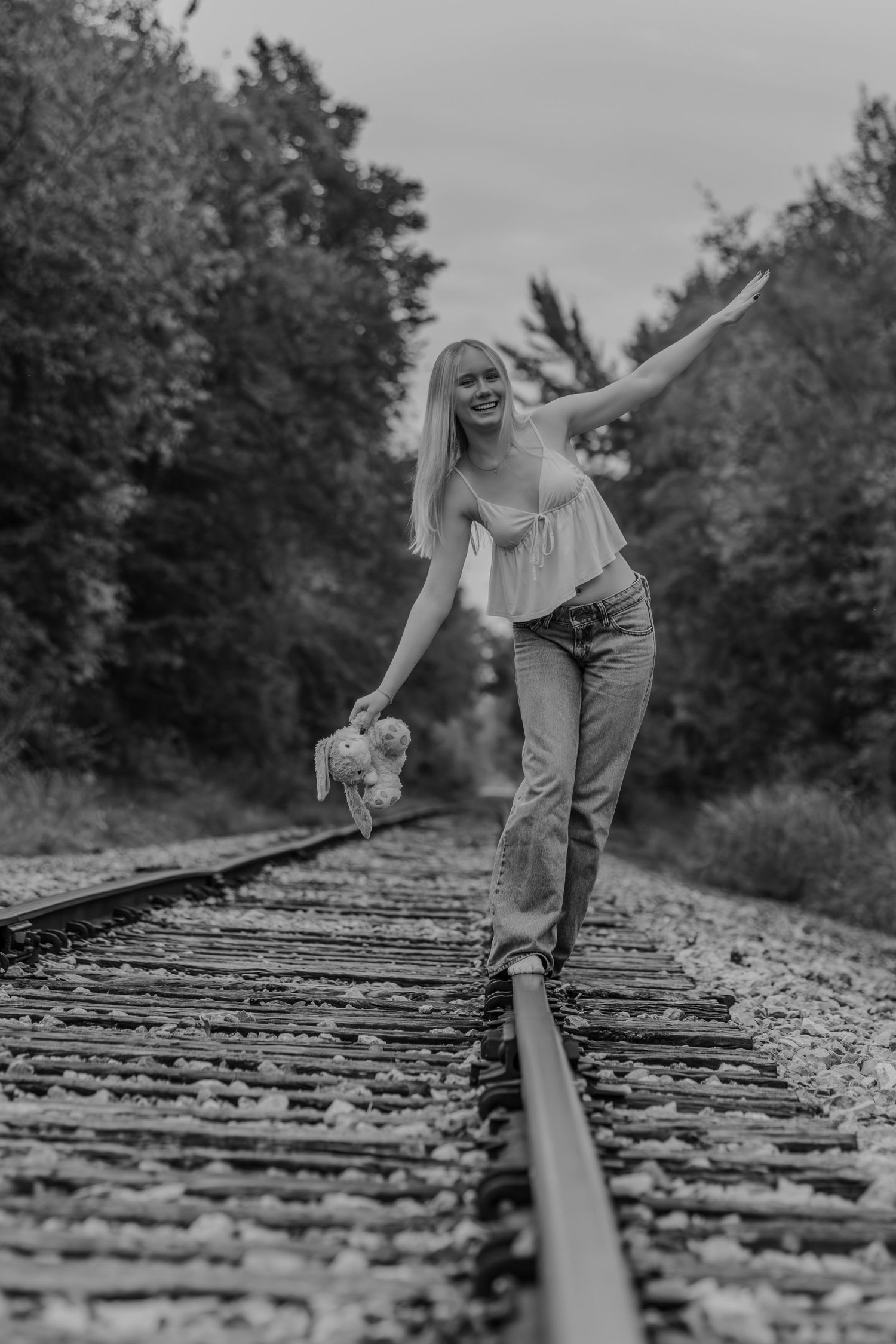 Black and white photo sequence showing a person balancing and walking along train tracks in a wooded area.