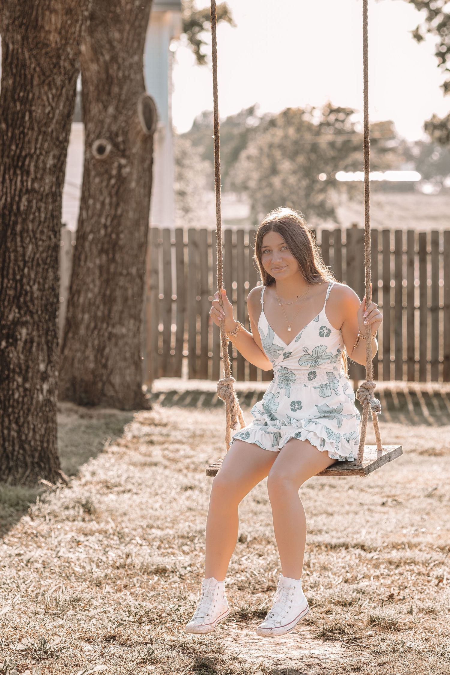 Person enjoying a swing in a backyard setting with sunlit trees.