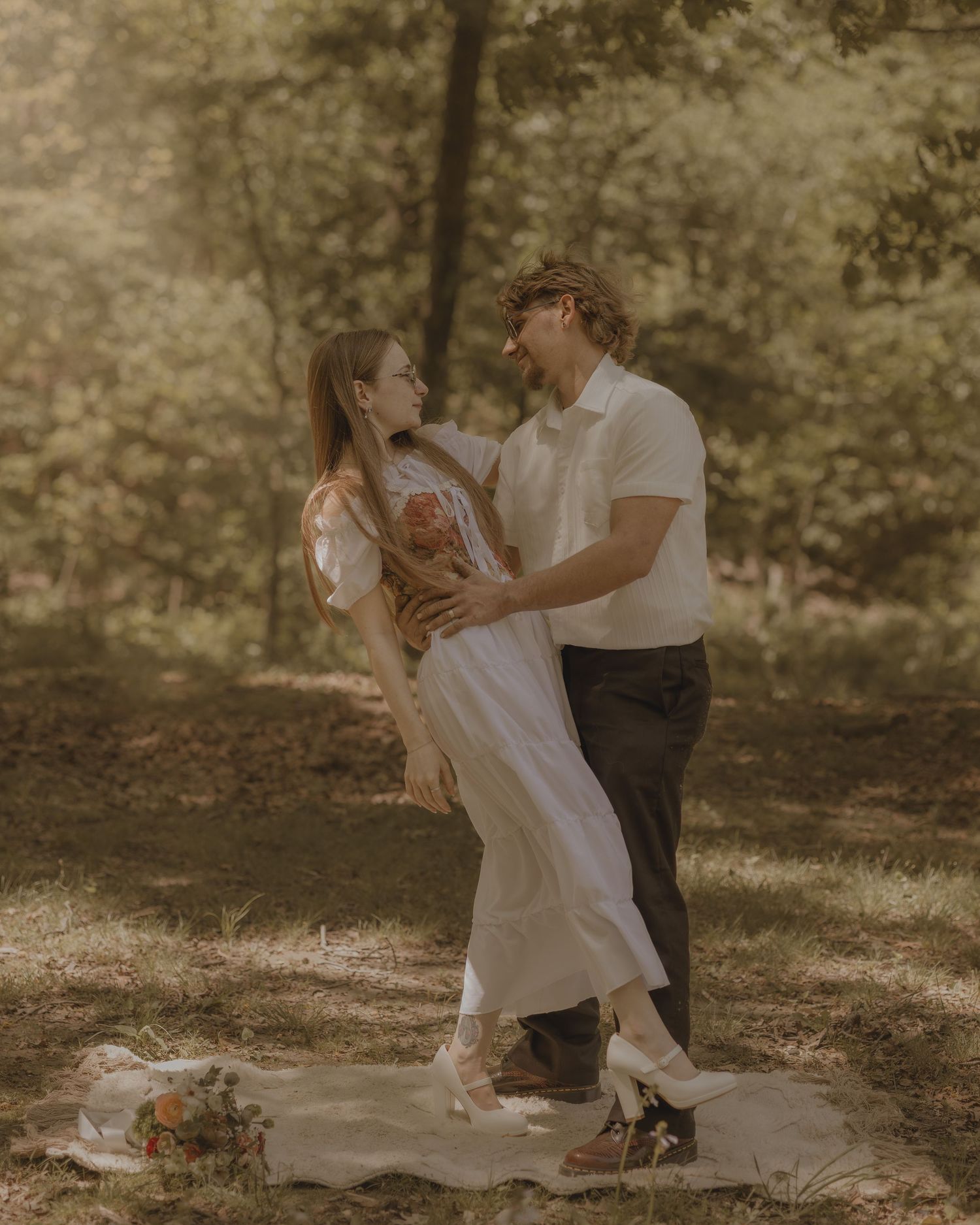 Couple embracing and smiling at each other in a romantic outdoor woodland engagement photoshoot.
