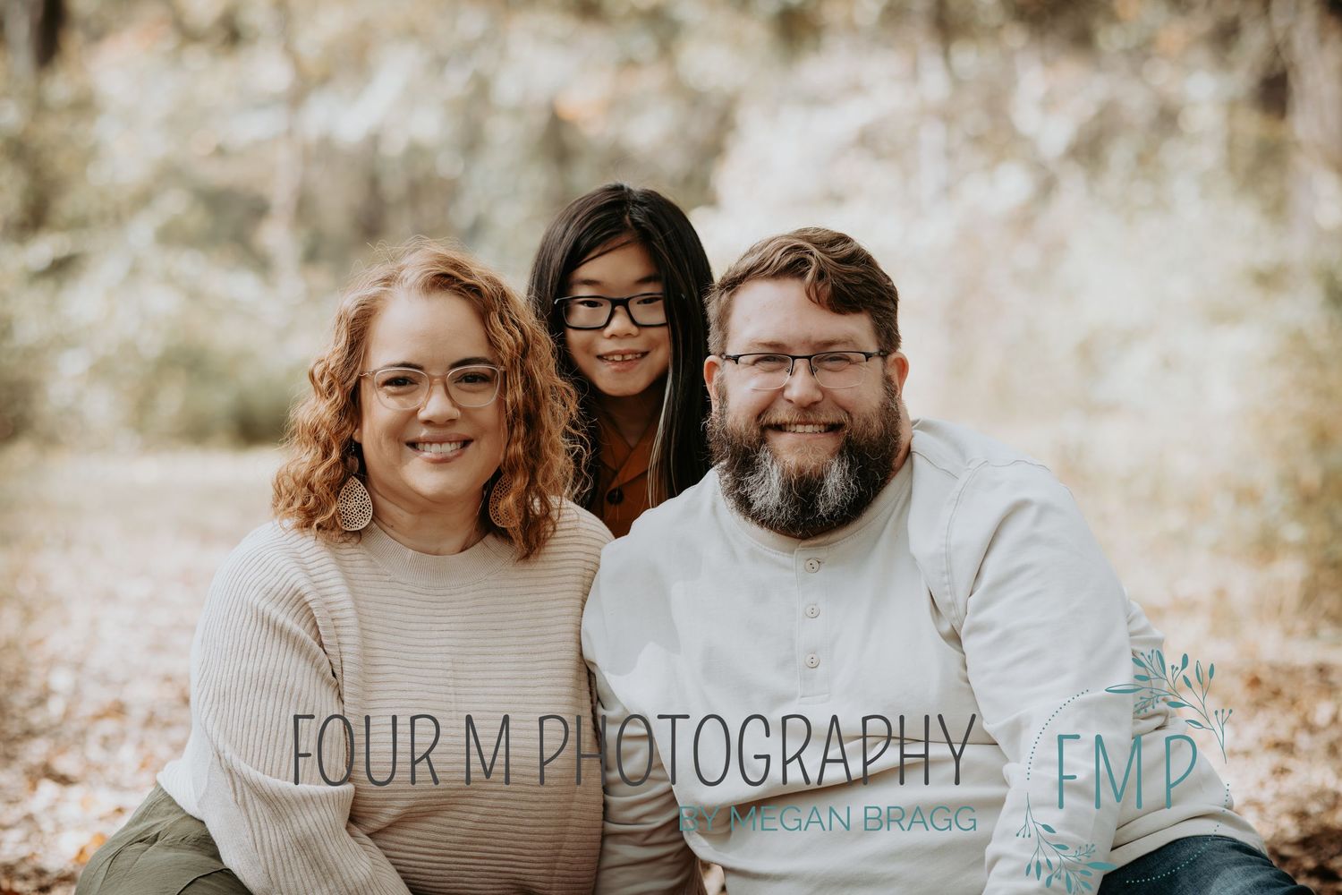 Outdoor family photo session captured in warm natural light with rustic stone wall backdrop.
