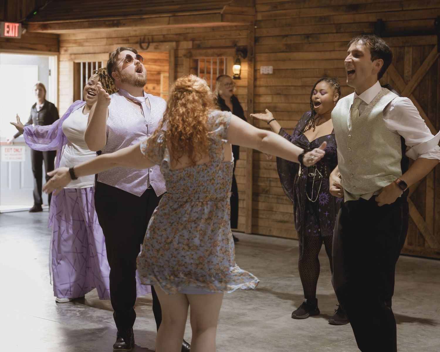 Guests laughing and dancing together at a rustic barn wedding reception celebration.