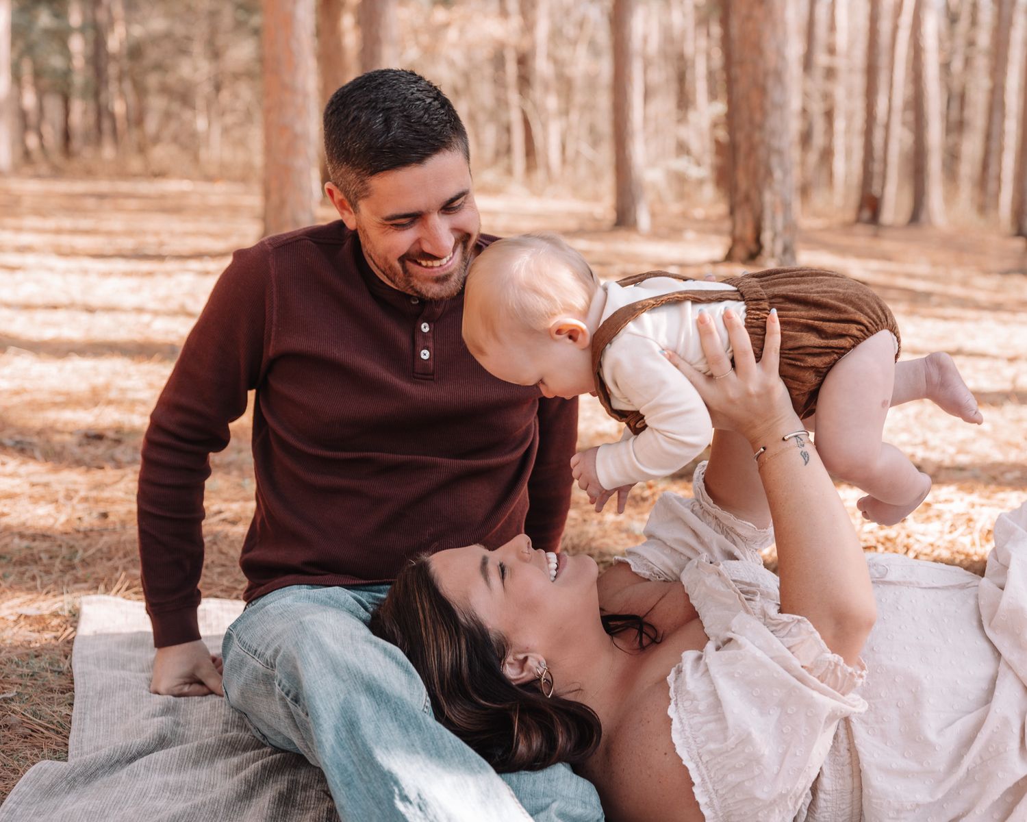A couple shares joyful moments together in a wooded area with warm lighting.