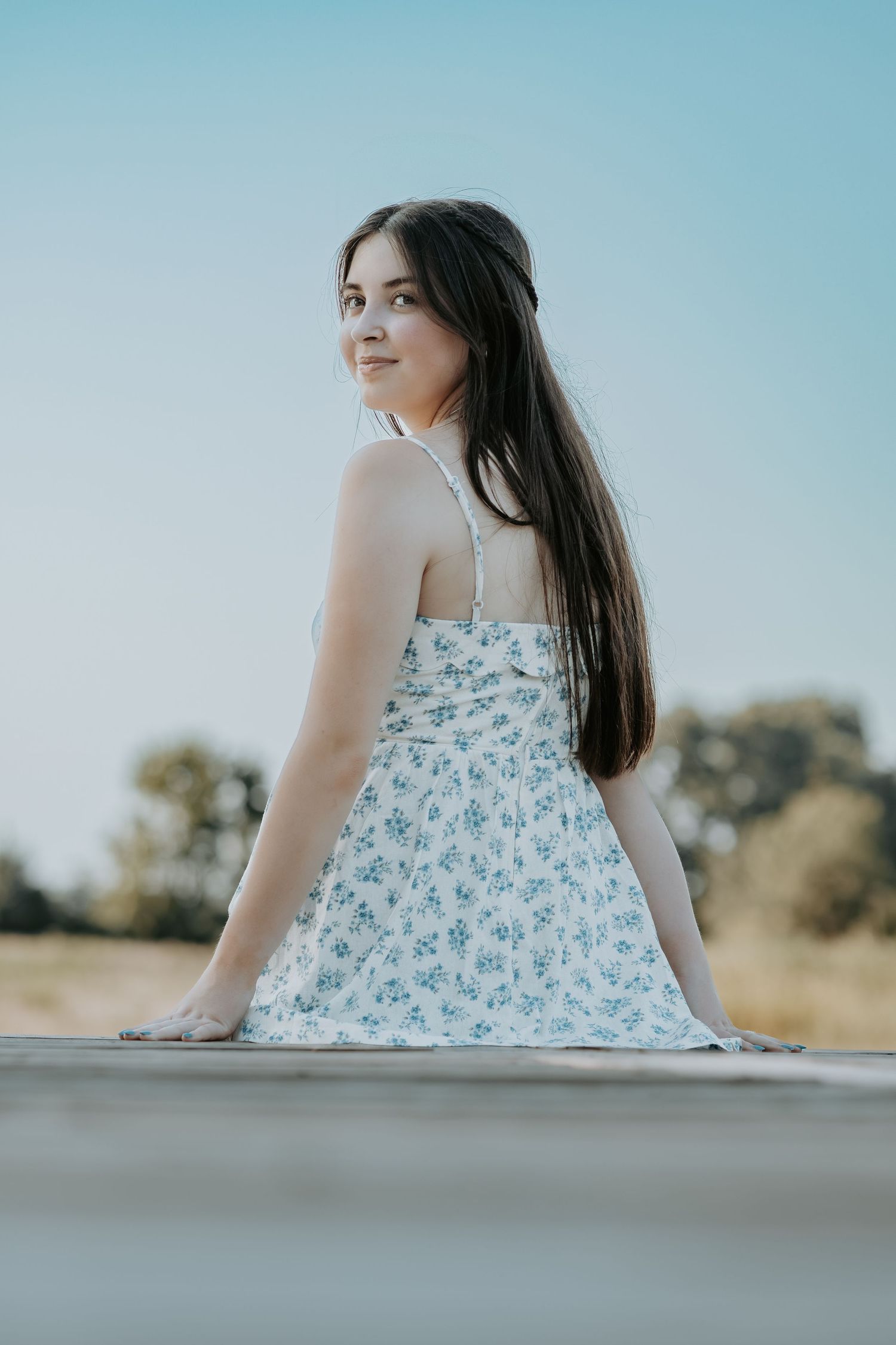 A white and blue floral dress creates a soft silhouette against a bright blue sky background.