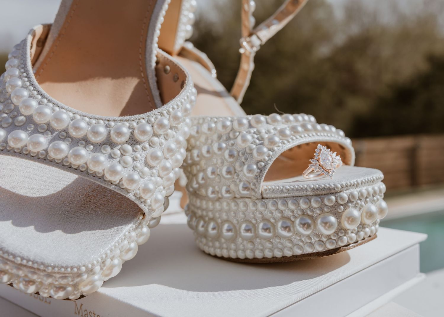 Elegant pearl-encrusted bridal platform wedge sandals with ankle strap, adorned with white pearls on white background.