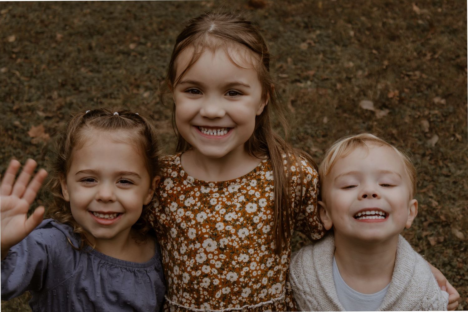 Children smiling and laughing together during an outdoor autumn photo session.