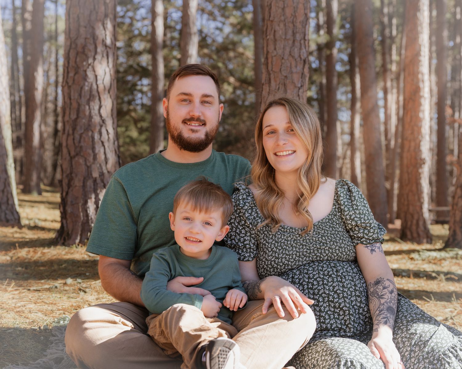 Happy family moments captured during an outdoor maternity photoshoot in a pine forest.