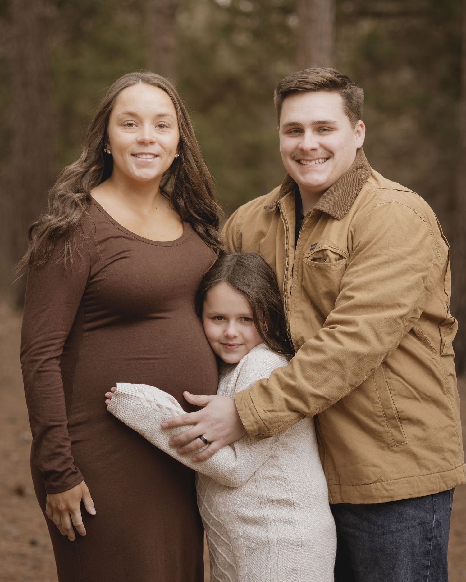 A maternity photo session showing a couple in brown and tan clothing posing together outdoors.