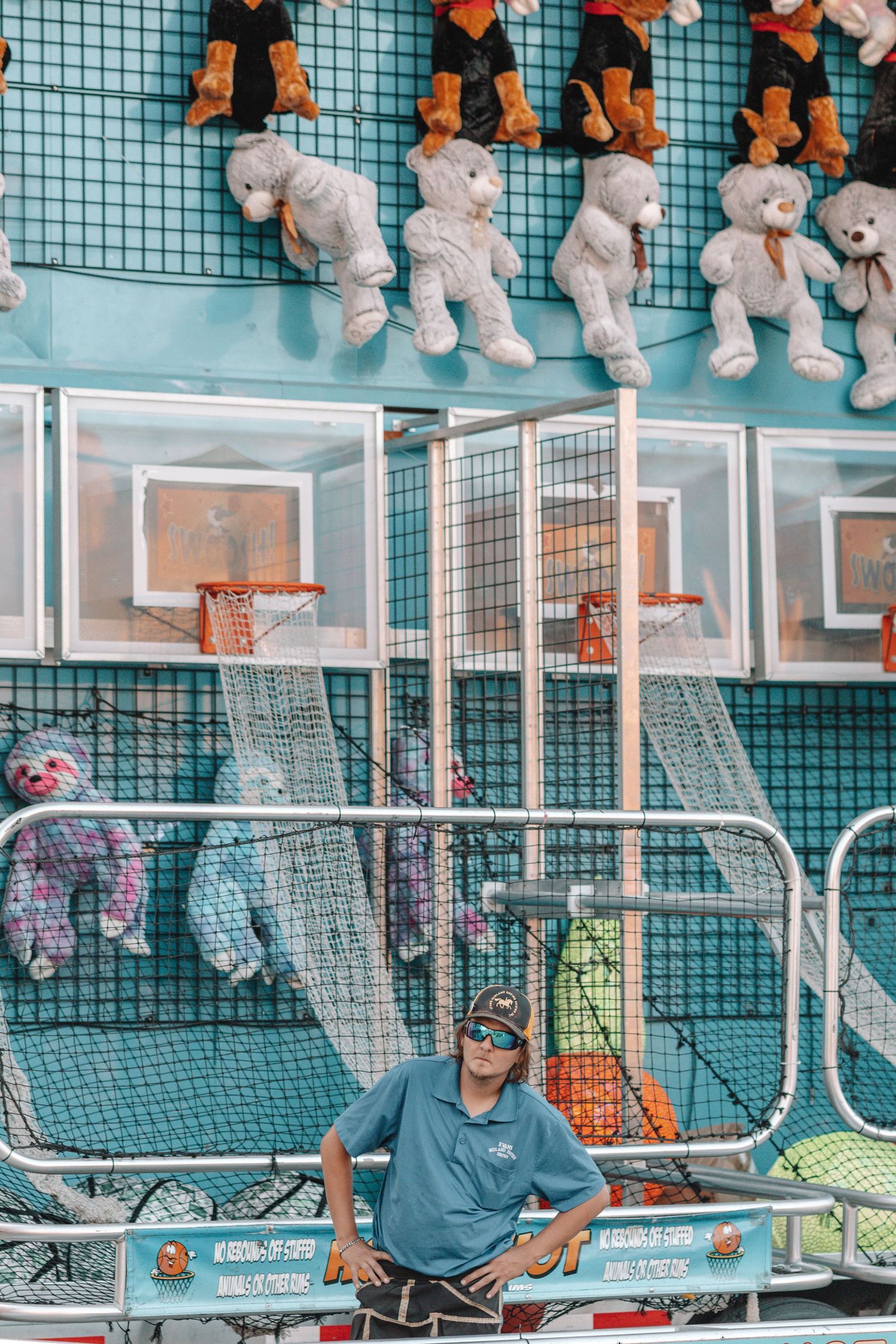 Display case filled with plush toys and stuffed animals against a blue tiled wall at a carnival game.