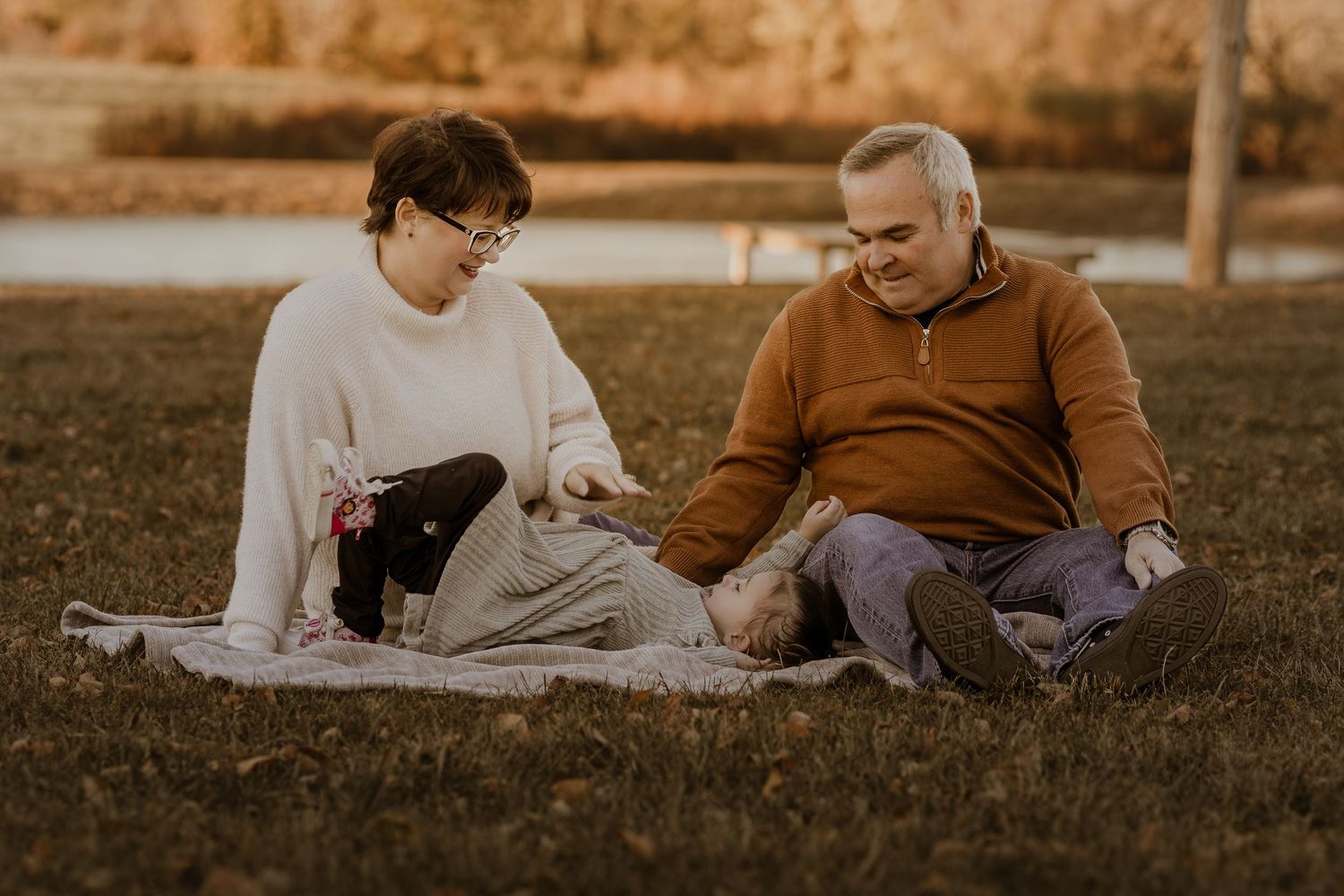 Family relaxes together on grass during golden hour outdoor photography session.