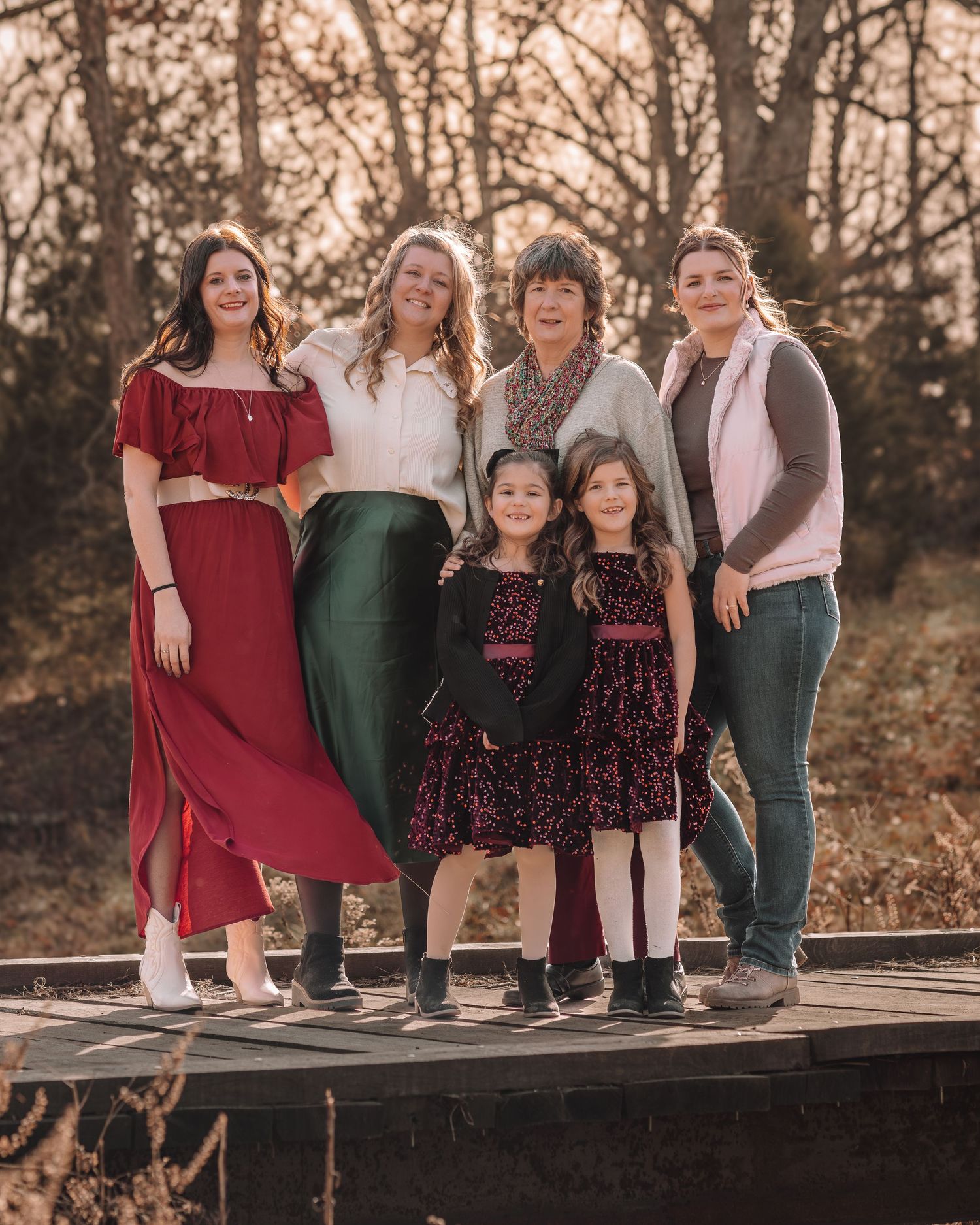 A group sits together on a wooden deck during sunset wearing coordinated burgundy, green and floral outfits.