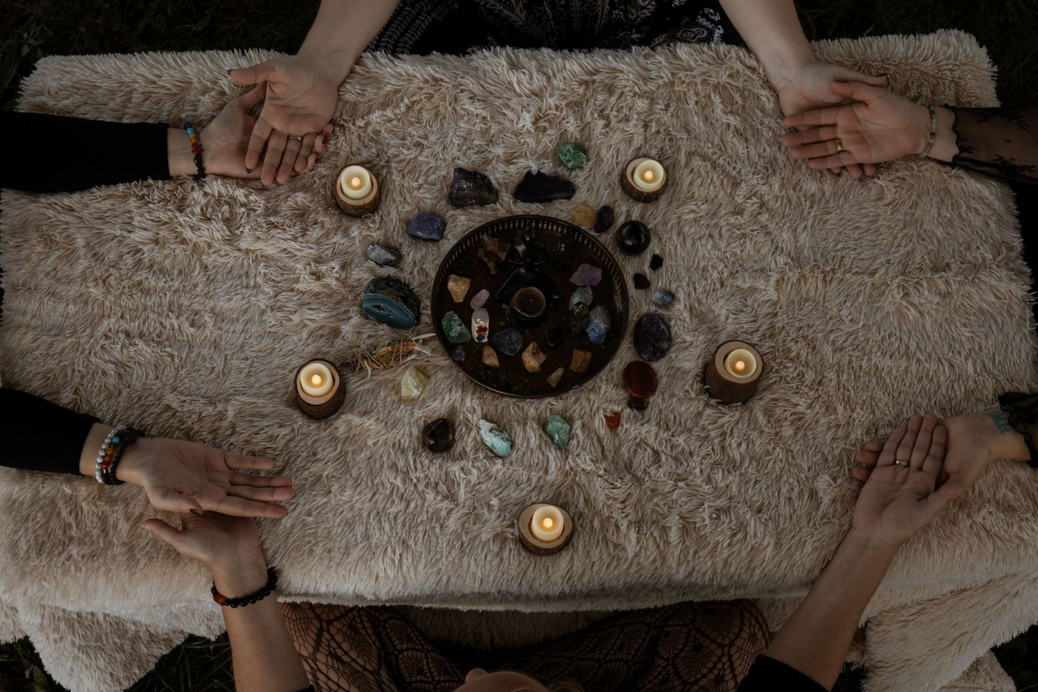 Hands holding buttons arranged on a textured beige surface in an artistic layout.