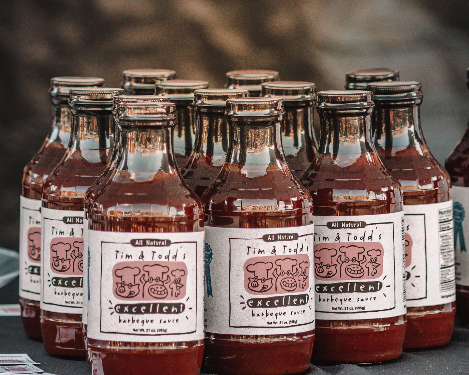 Rows of glass jars filled with red strawberry jam or preserves lined up on a rustic wooden surface.