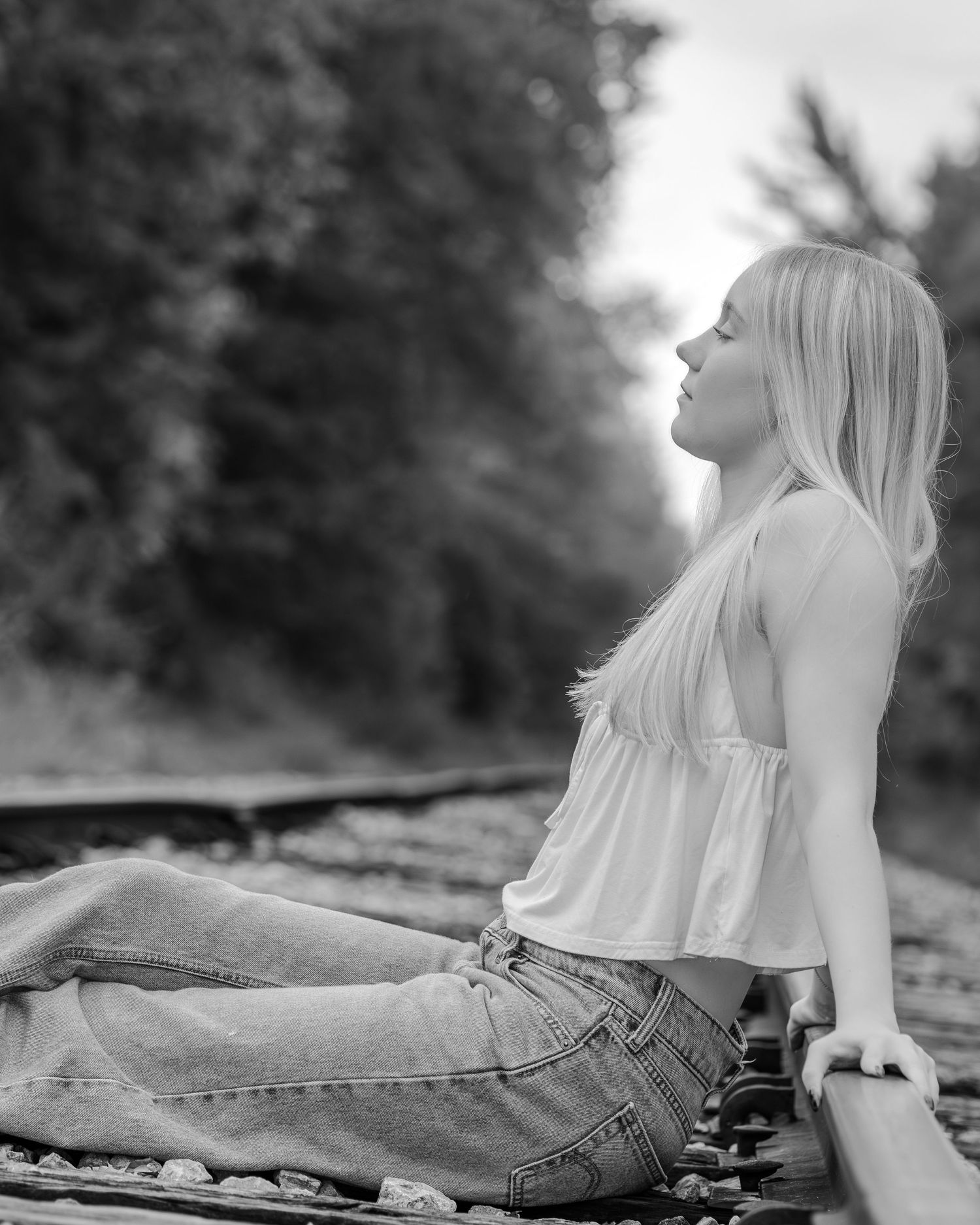 Black and white artistic photo sequence showing a person lying down in jeans against a blurred outdoor background.