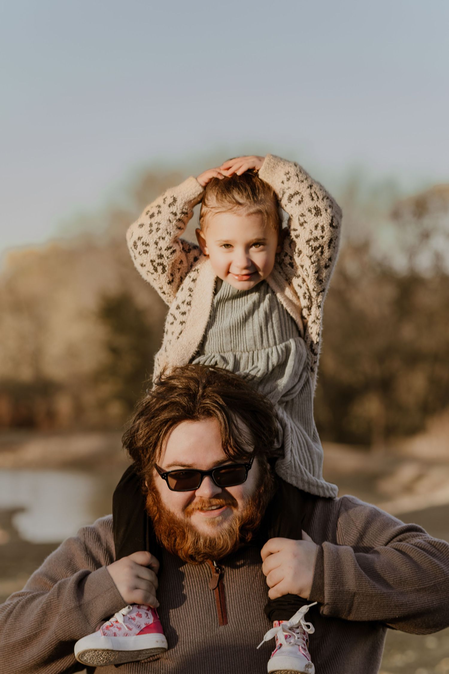 A playful family moment captured outdoors during sunset with warm lighting.