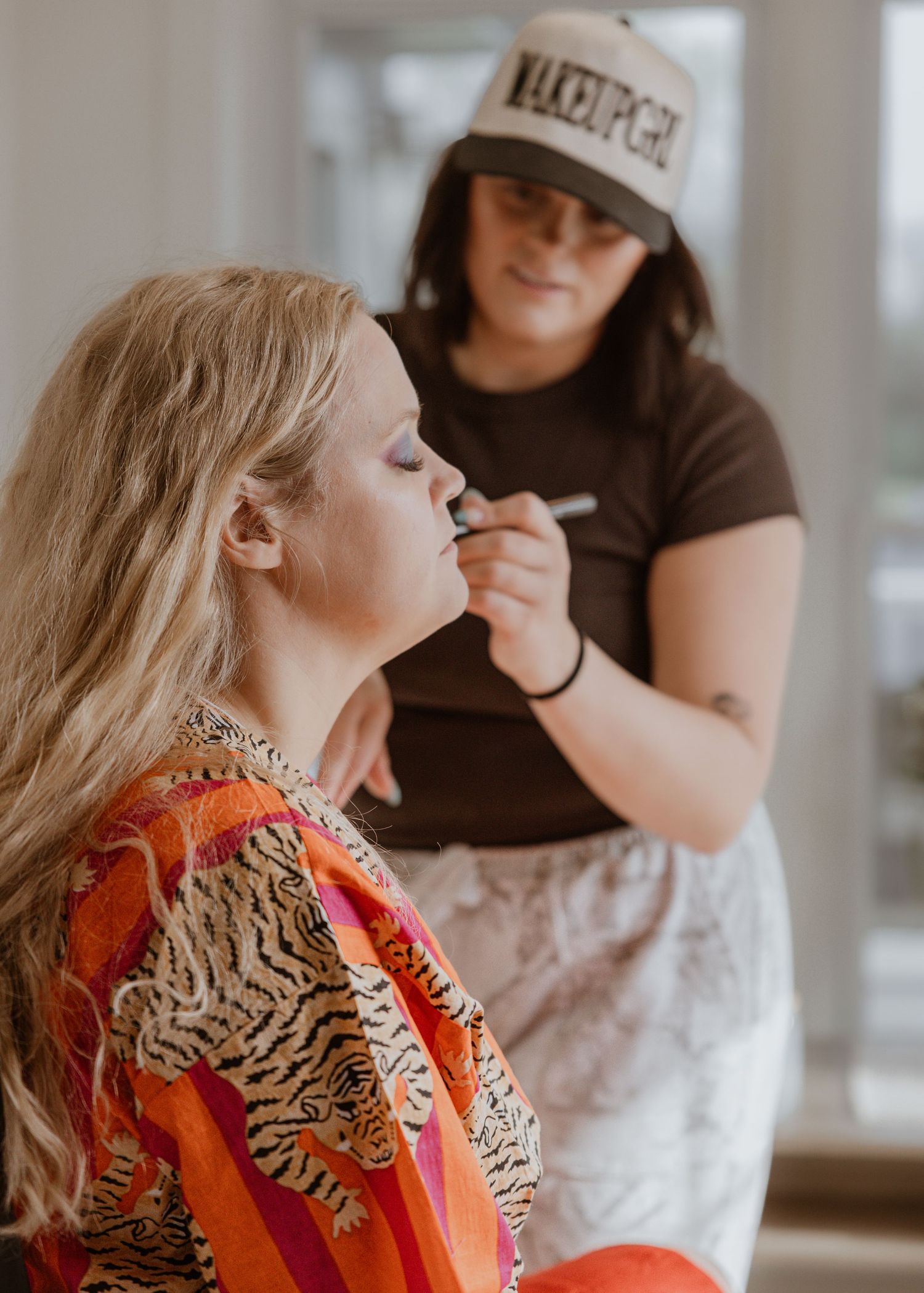 Professional makeup artist applying cosmetics to a blonde woman before a special event or wedding.