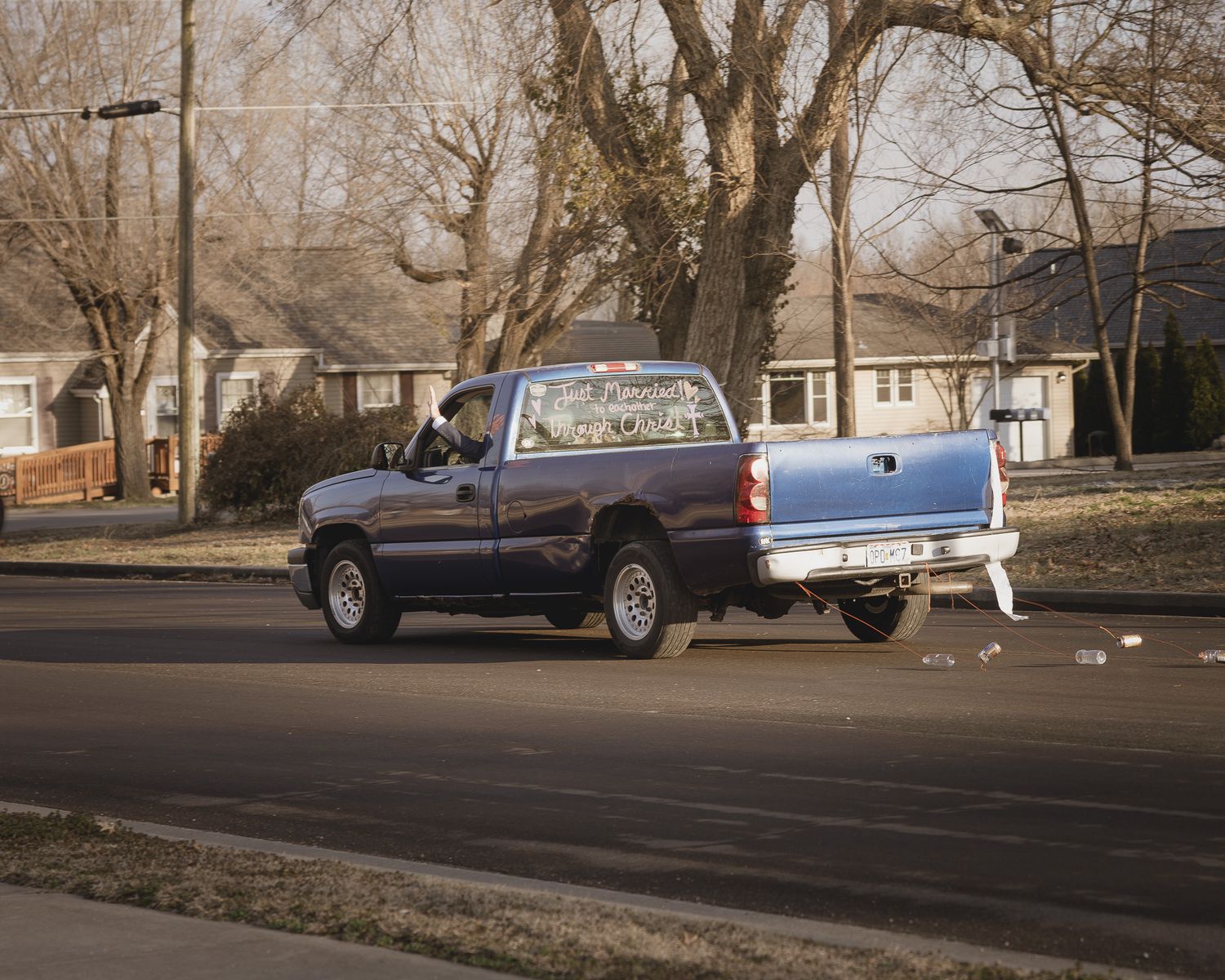 A panoramic view of parked cars and houses along a residential street on an overcast day.