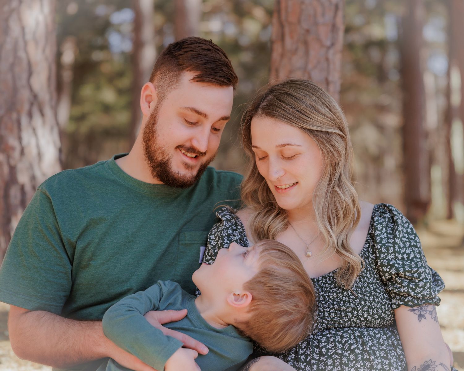 A family lying together on a blanket in a pine forest sharing joyful moments together.