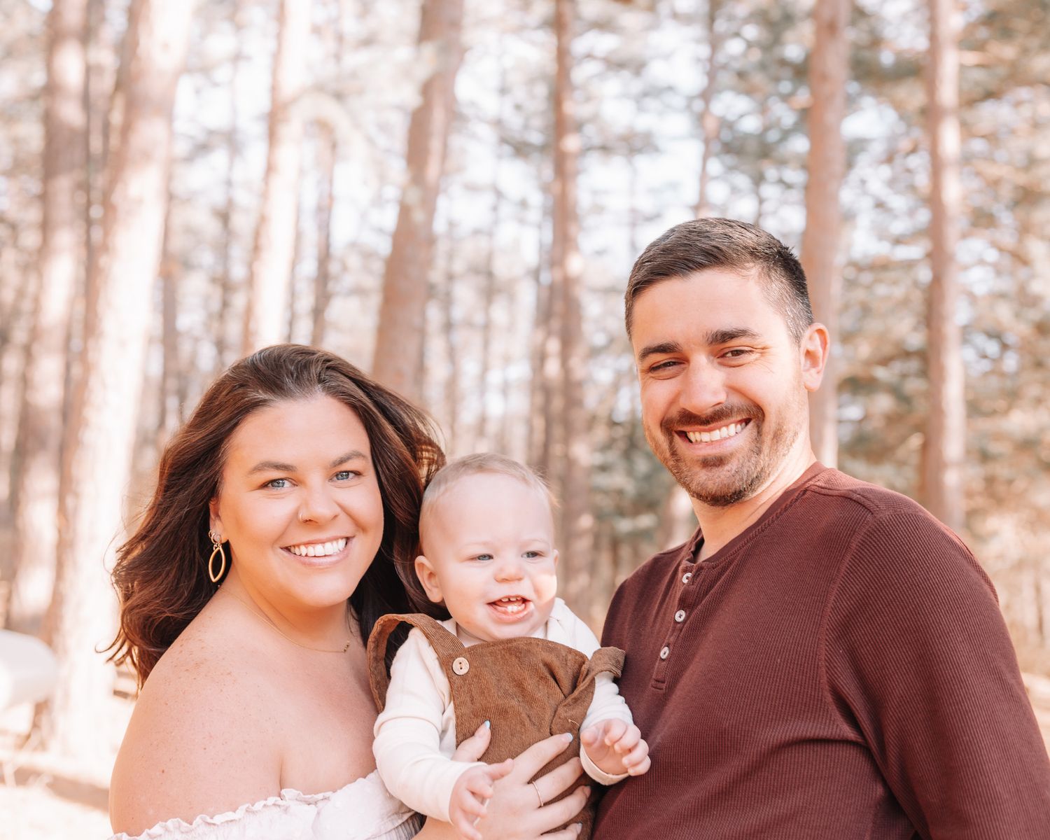 Family photoshoot in a pine forest with warm lighting and natural outdoor setting.