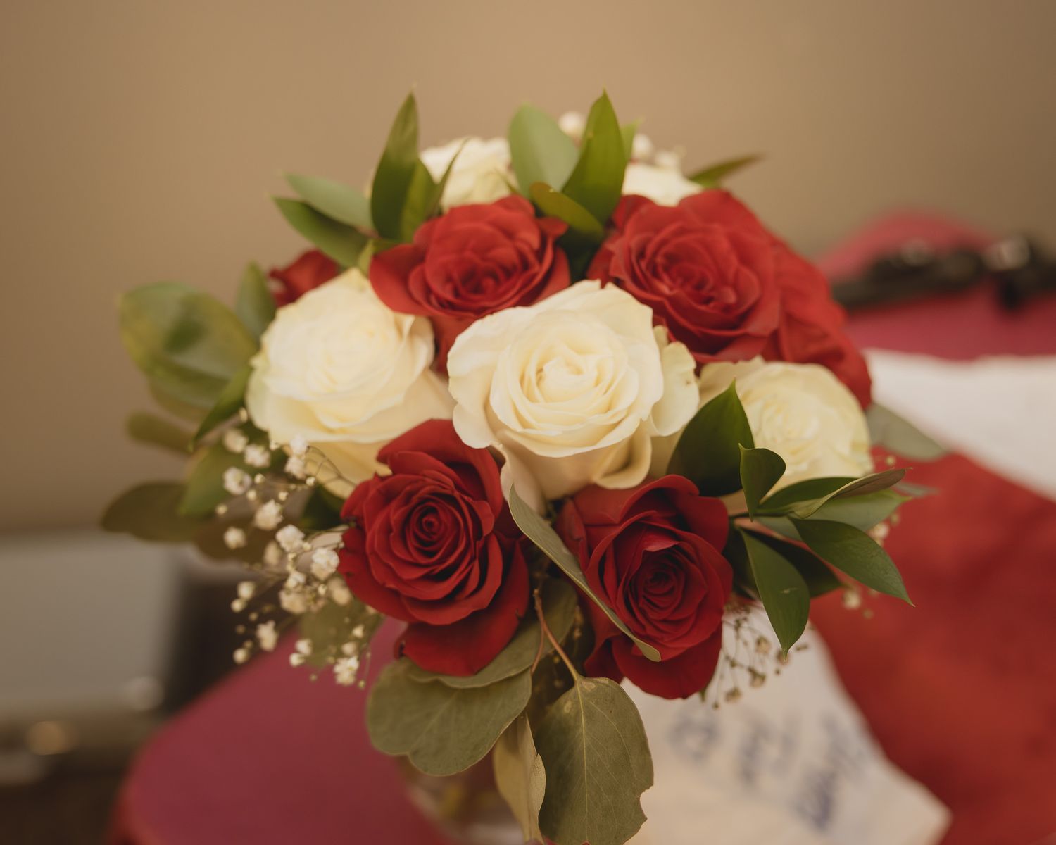 A romantic floral arrangement featuring red and white roses with delicate baby's breath and green foliage.