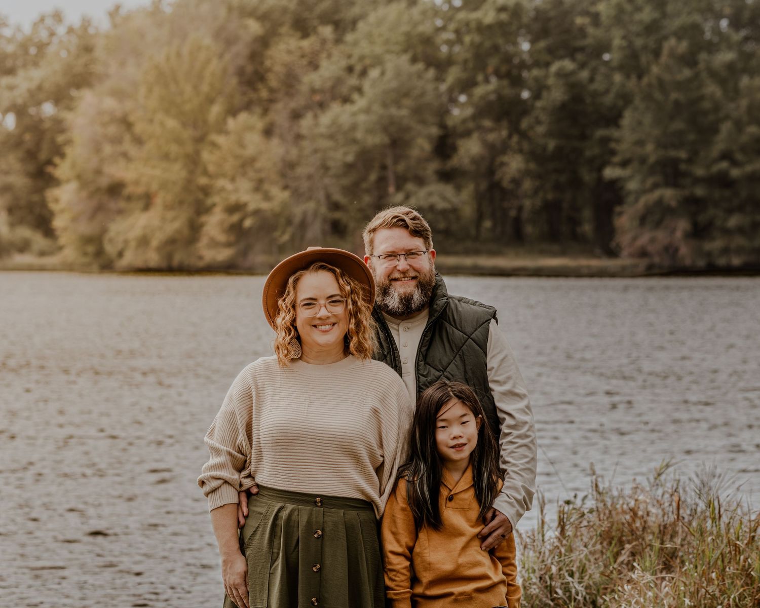 A series of warm-toned outdoor photos showing people embracing by a lake with autumn foliage in the background.