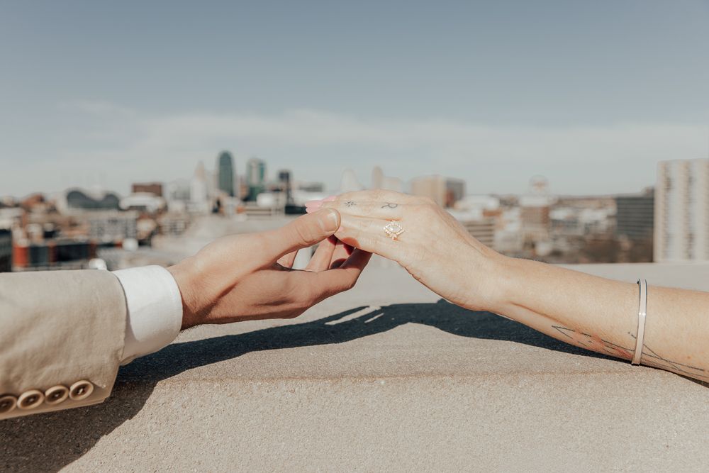 Two hands reaching out and touching against a blurred city skyline background in warm sunlight.