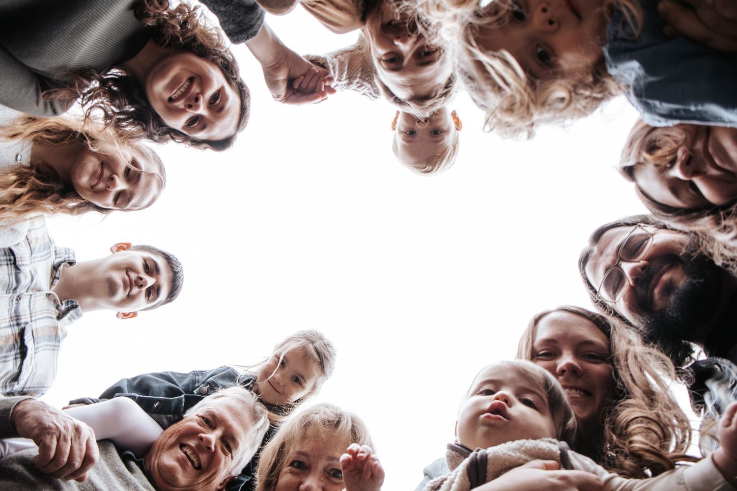 Group of diverse people forming a circle huddle viewed from below, smiling together in a team unity concept.