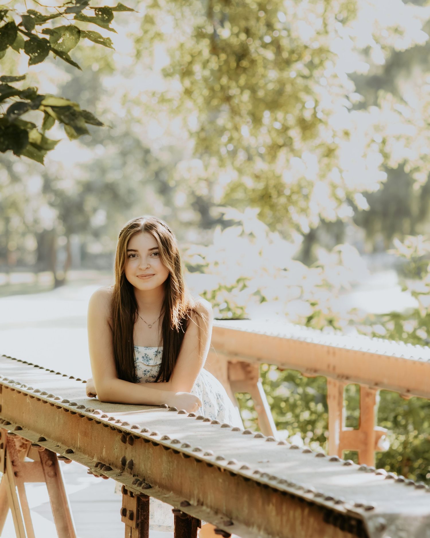 A dreamy outdoor portrait series featuring a person posing beside rustic wooden railings under sunlit foliage.