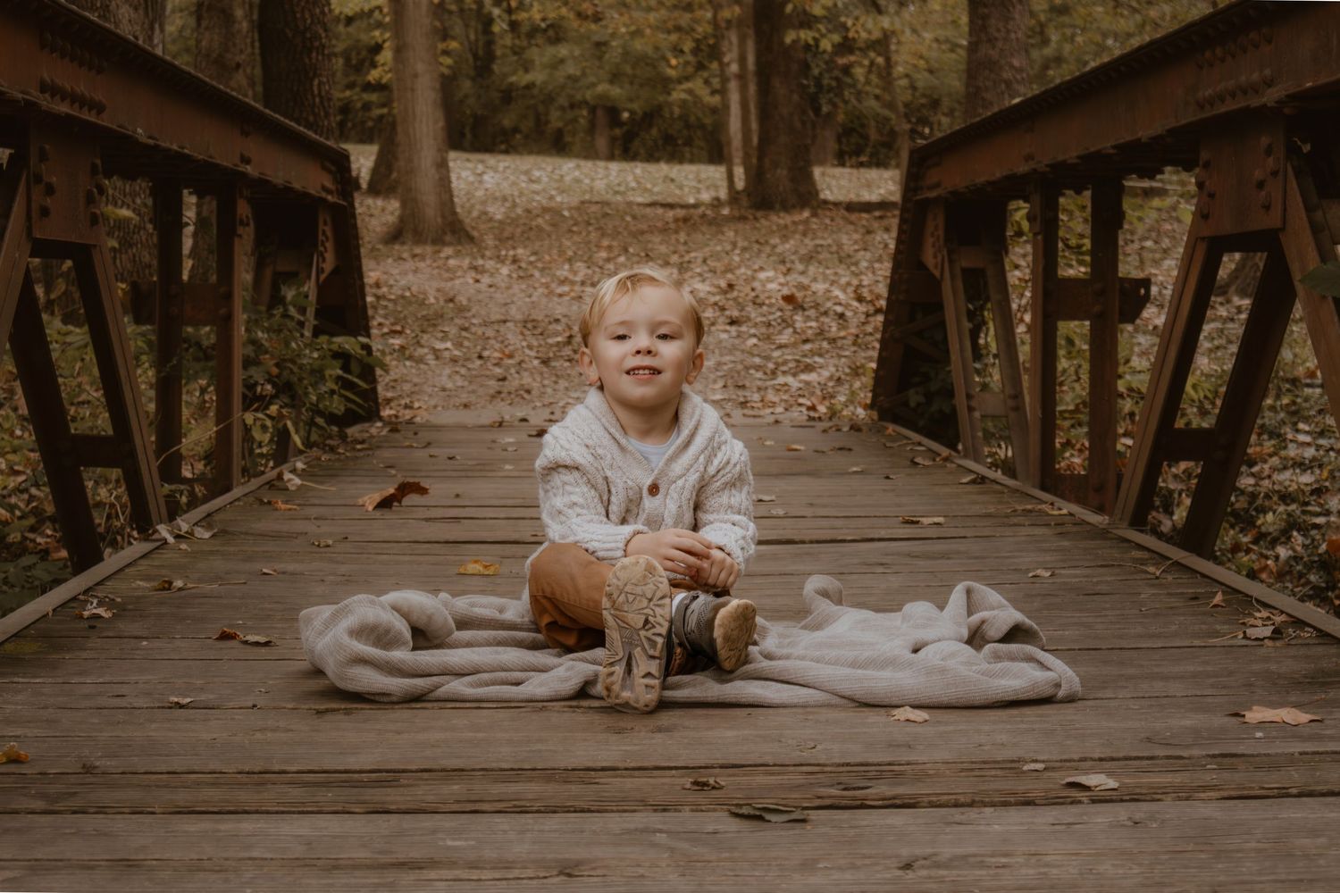 A series of sepia-toned photographs showing a child sitting on a wooden deck surrounded by trees.