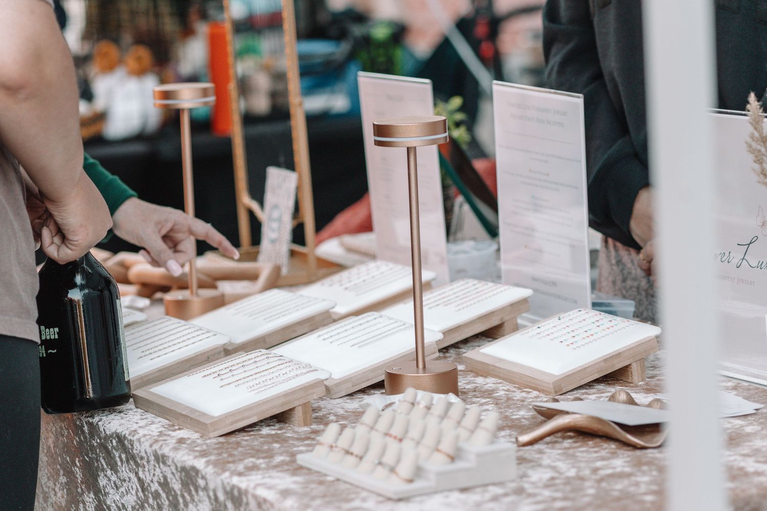 Close-up of hands arranging menu cards and table settings on a rustic wooden surface at an event.
