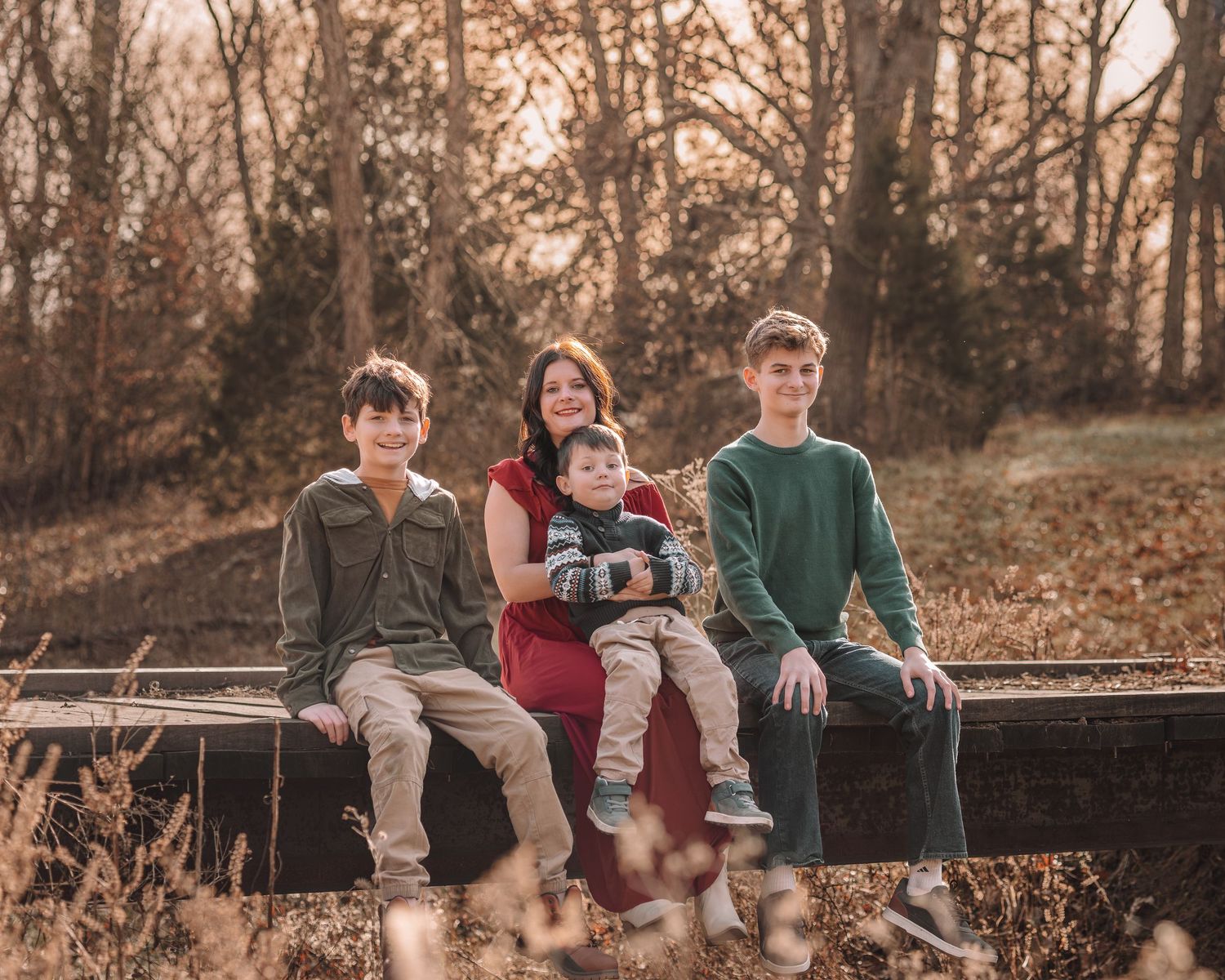 A group of friends sit casually on a wooden fence at sunset during autumn, creating a warm and nostalgic scene.