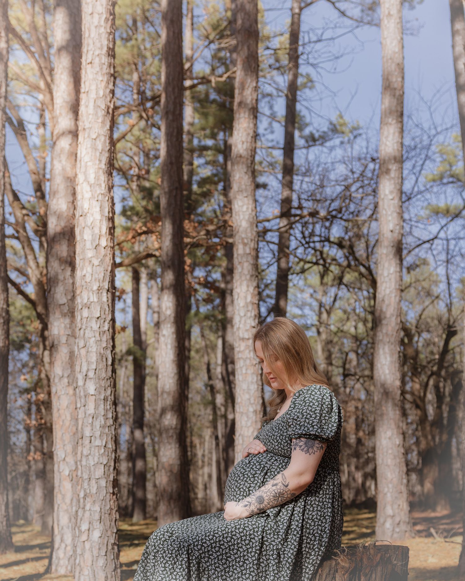 A forest maternity session with a flowing dress captures movement against towering pine trees.
