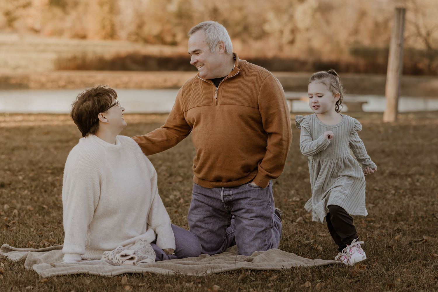 Family members sit together on a blanket during a golden hour outdoor photo session.