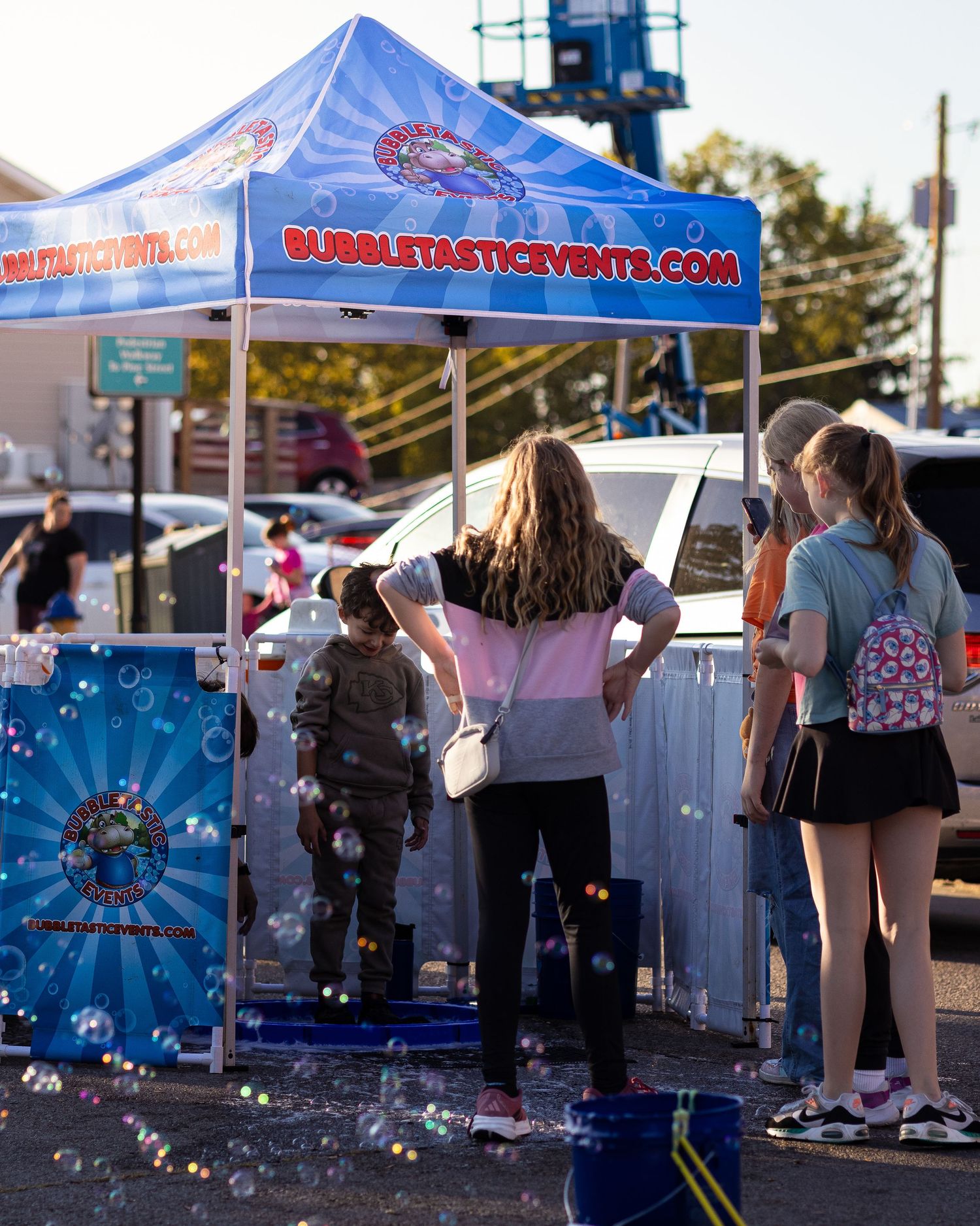 Blue vendor tent with bubble-making activities and equipment set up at an outdoor festival.