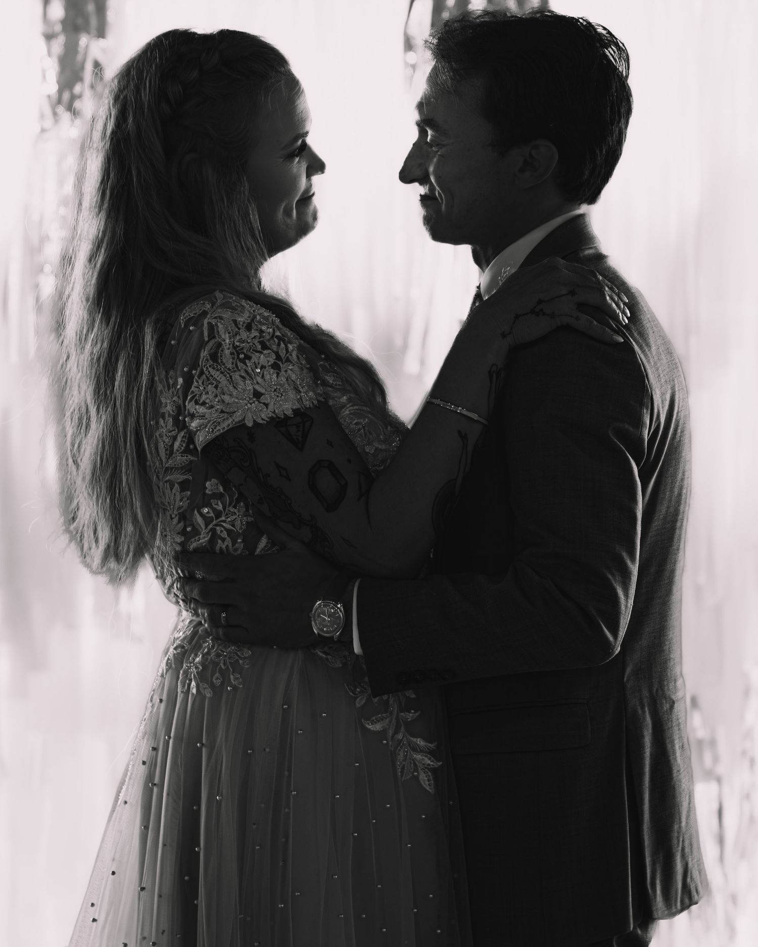 Black and white romantic portrait of bride and groom gazing at each other at wedding reception.